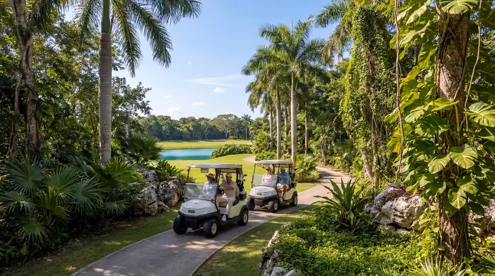 Carritos de golf recorriendo un sendero entre vegetación tropical hacia el fairway